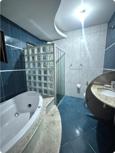 a bathroom with a tub and a sink at Refúgio Aconchegante com Varanda para Natureza in Resende