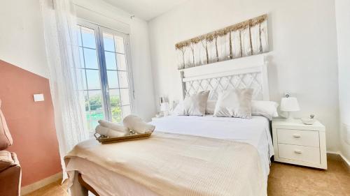 a white bedroom with a large bed and a window at Marife Home in Guillena