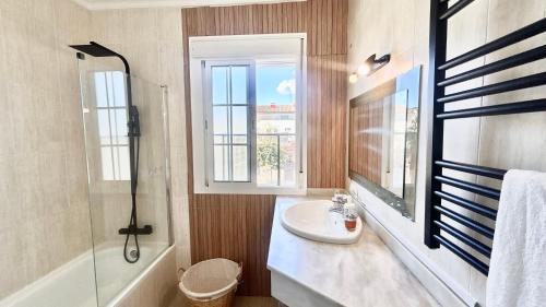 a bathroom with a sink and a shower and a window at Marife Home in Guillena