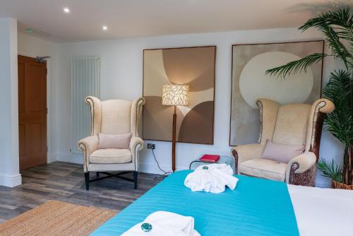 a bedroom with two chairs and a bed with towels at Beachcliff Rooms & Apartments in Cardiff