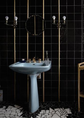a bathroom with a sink and a black tiled wall at La Maison Tataouine in Moux