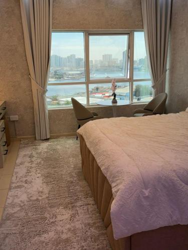 a bedroom with a large bed and a large window at High-floor Luxury Apartment! in Ajman 