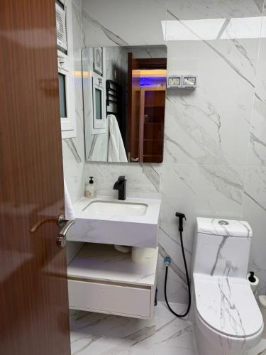 a bathroom with a sink and a toilet and a mirror at High-floor Luxury Apartment! in Ajman 