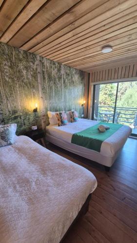 two beds in a room with wooden floors at Lodge Los Bosques in Matanzas