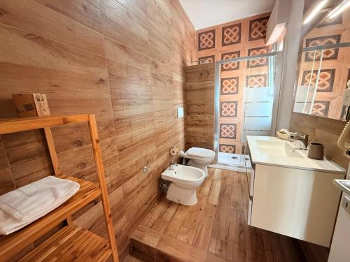 a bathroom with wooden walls and a toilet and a sink at Home Syrakos in Syracuse