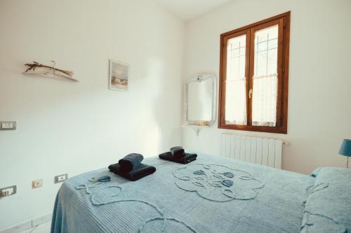 a bedroom with a bed with a blue blanket and a window at Seaside Beach House with Private Parking in Punta Marina