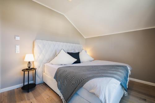 a bedroom with a bed and a lamp on a wooden floor at Strandgeflüster deluxe in Zingst