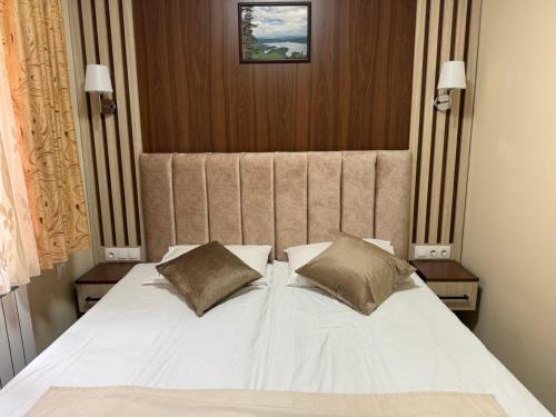 a large white bed with two pillows on it at Ивелия Къща за гости in Dospat