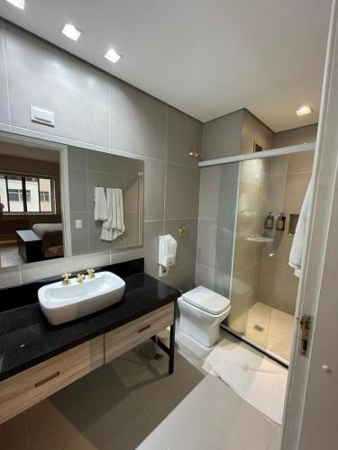 a bathroom with a sink and a toilet and a shower at Flat no coração de Joinville in Joinville