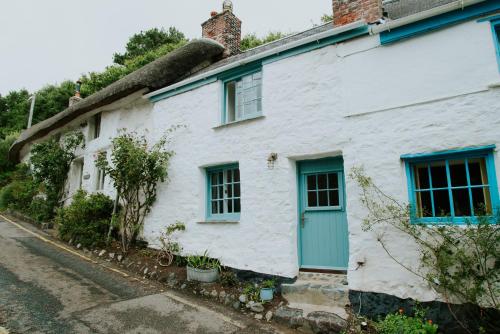 a white cottage with a thatched roof at Cliff Cottage in Cadgwith