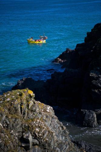 a boat in the water next to some rocks at Cliff Cottage in Cadgwith