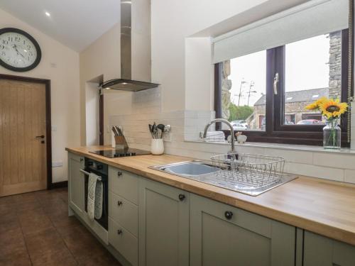 a kitchen with a sink and a clock on the wall at Woodside Barn in Ulverston