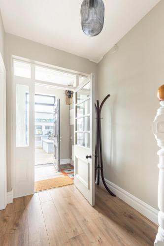 a hallway with a white door and a room with wood floors at The Wild Atlantic Townhouse in Enniscrone