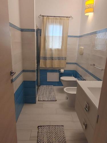 a blue and white bathroom with a toilet and a shower at Casa Dessi in Tanaunella