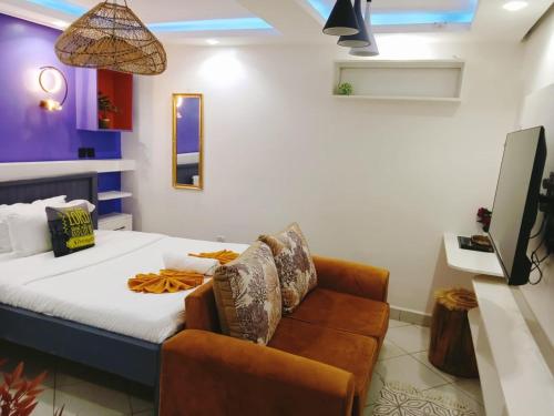 a bedroom with a bed and a couch and a tv at Shelvic Resort Ruiru in Ruiru