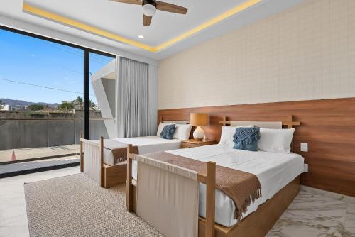 a bedroom with two beds and a large window at Bahiban Residences Oceanfront by Monyxbnb in Cruz de Huanacaxtle