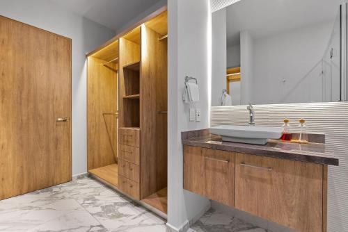 a bathroom with a sink and a wooden door at Bahiban Residences Oceanfront by Monyxbnb in Cruz de Huanacaxtle