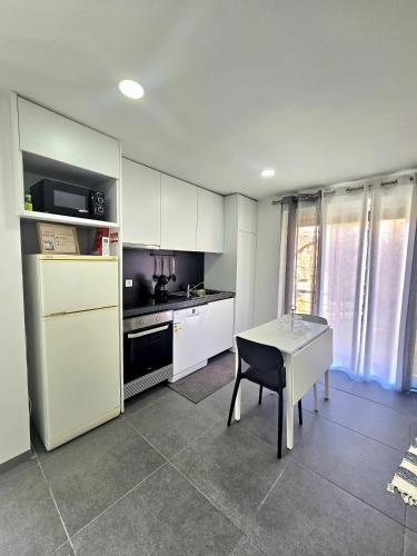 a kitchen with white cabinets and a table with a chair at Casa Vinhas - O teu refúgio no coração da cidade in Macedo de Cavaleiros