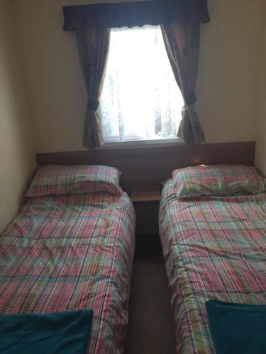 two beds in a small room with a window at Paddocks 4 in East Mersea
