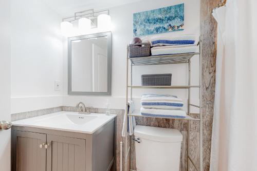 a bathroom with a sink and a toilet and a mirror at Seas the Day OBX in Kitty Hawk Beach