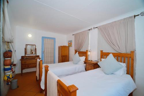 ein Schlafzimmer mit zwei Betten und einem Spiegel in der Unterkunft Katonkel in Paternoster