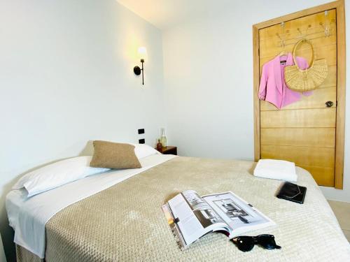 ein Schlafzimmer mit einem Bett, auf dem ein Buch und eine Sonnenbrille liegen in der Unterkunft Hotel Bombay in Baños