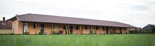 a large building with a grass field in front of it at Relax Apartmanház in Mórahalom