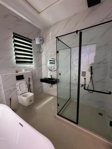 a bathroom with a glass shower and a toilet at Danjo Shortlets in Aja