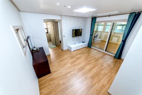 a living room with wood floors and a tv at Hu An Stay Hotel in Seogwipo