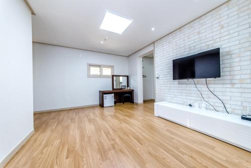a living room with a flat screen tv on a brick wall at Hu An Stay Hotel in Seogwipo