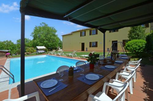 a long wooden table with chairs and a pool at Casa Sofi - Happy Rentals in Monticiano