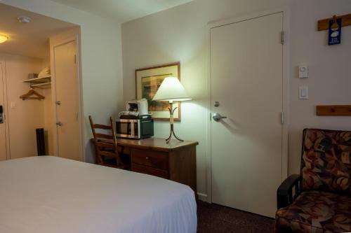 a hotel room with a bed and a desk with a microwave at Cahilty #211 home in Sun Peaks