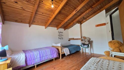 a bedroom with two beds and a wooden ceiling at La Colina in Río Mayo