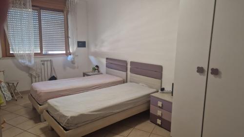 a bedroom with two beds and a dresser and a window at Caty House in Nettuno