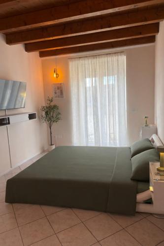 a bedroom with a large green bed in front of a window at Garda Green - Luxury Apartment in Lonato