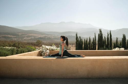 a woman sitting on a wall in a yoga pose at Villa A Atlas Retreat Luxury B and B Beni Mellal in Beni Mellal