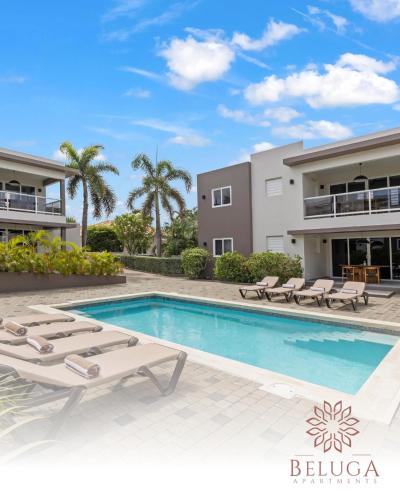 a villa with a swimming pool and lounge chairs at Beluga Apartments Curacao - nabij Willemstad & Mambo Beach in Willemstad