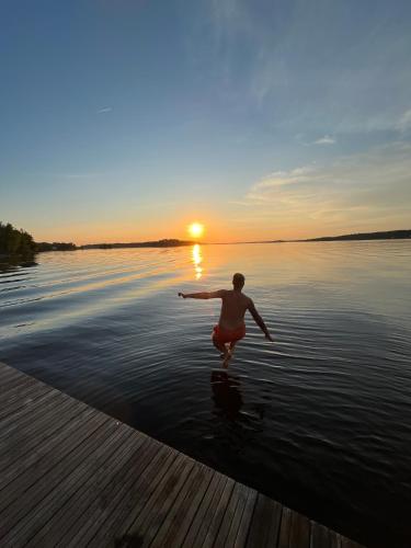 a man is running in the water at sunset at Rindö Hamn Bed & Breakfast in Vaxholm