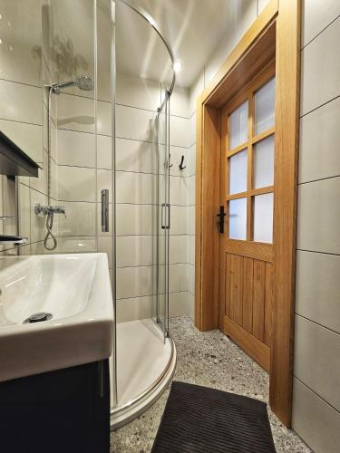a bathroom with a sink and a shower and a tub at Apartament Rysulówka 76 in Kościelisko