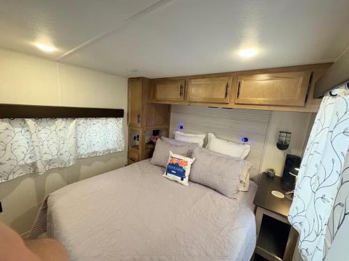 a small bedroom with a bed in an rv at Bumblebee - Luxury Destination Trailer in Canyon Lake