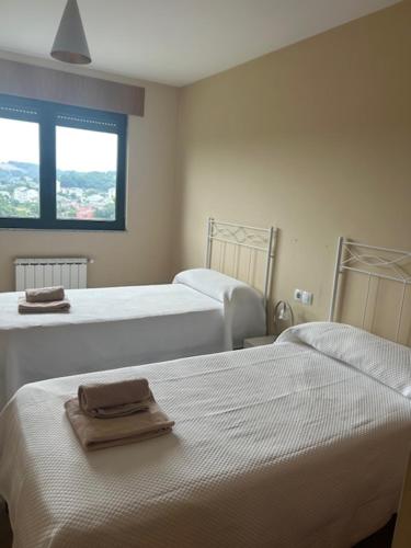 a bedroom with two beds with towels on them at Piso moderno in Sarria