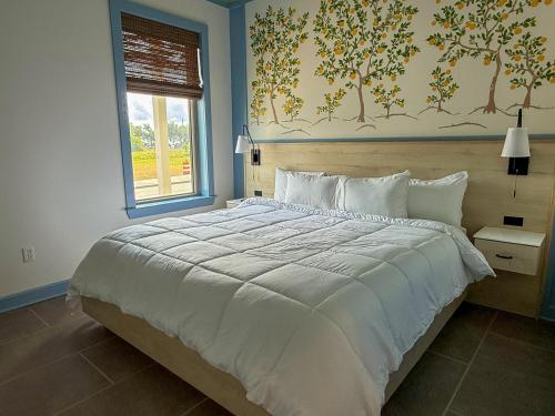 a bedroom with a large white bed and a window at The Pass Bungalows in Pass Christian