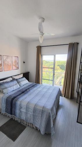 a bedroom with a large bed and a large window at Refúgio perfeito em Itatiba in Itatiba