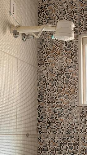 a bathroom with a shower with a tiled wall at Casa Espaçosa e Aconchegante com 4 camas, 3 quartos in Juazeiro do Norte