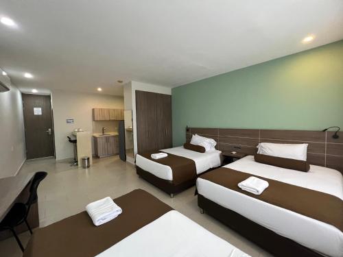 a hotel room with two beds and a kitchen at Hausen Hotel - Suites in Montería