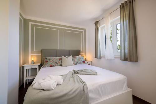 a bedroom with a large white bed with towels on it at Villa Alba Moscenicka Draga in Mošćenice