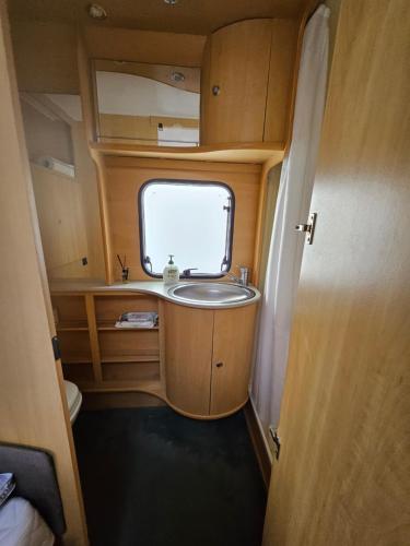 a bathroom with a sink and a window in an rv at Radbjerg privat camping in Væggerløse