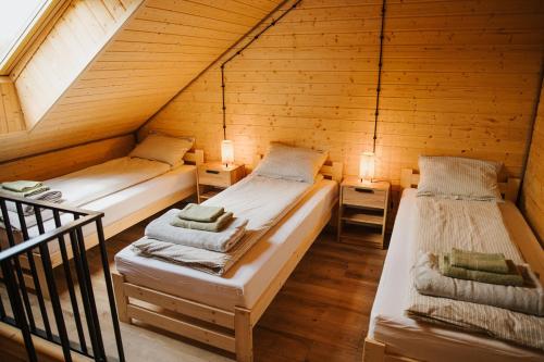 two beds in a wooden attic room with lights at PUŹNIAKÓWKA in Czarna