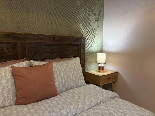 a bed with a wooden headboard and a lamp on a table at Vanito Art Escape in Nesebar