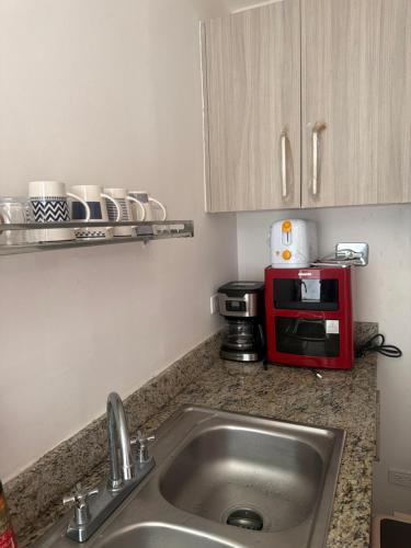 a kitchen counter with a sink and a red microwave at Playa dorodo in La Chorrera
